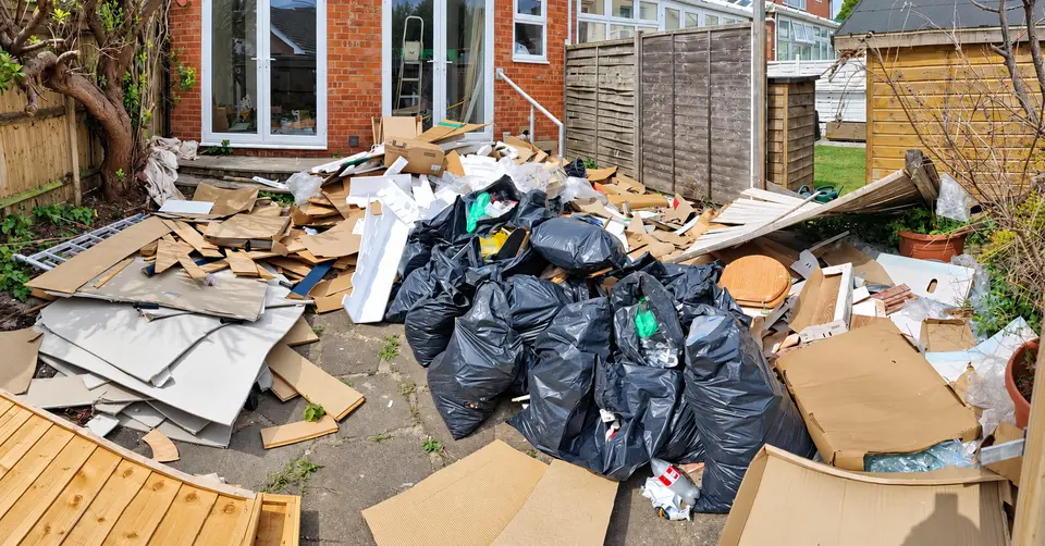 Before: a back patio buried under bin bags, cardboard, fence panels and builders waste